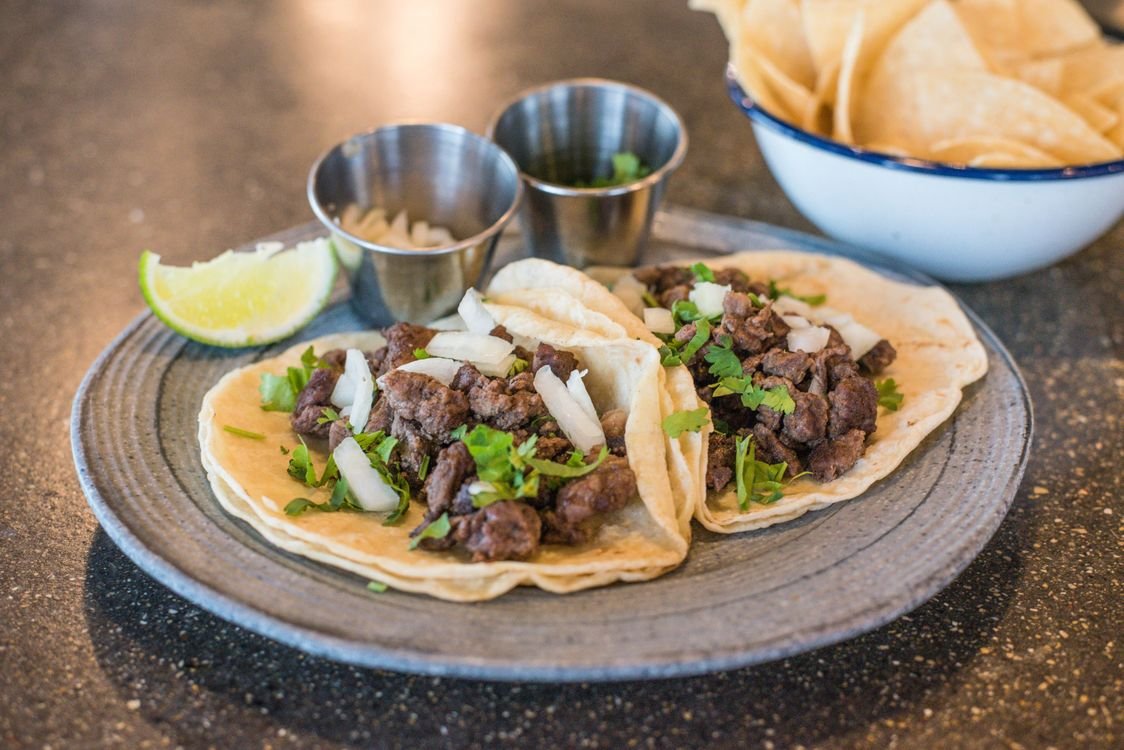 Beef tacos served with herbs and lime