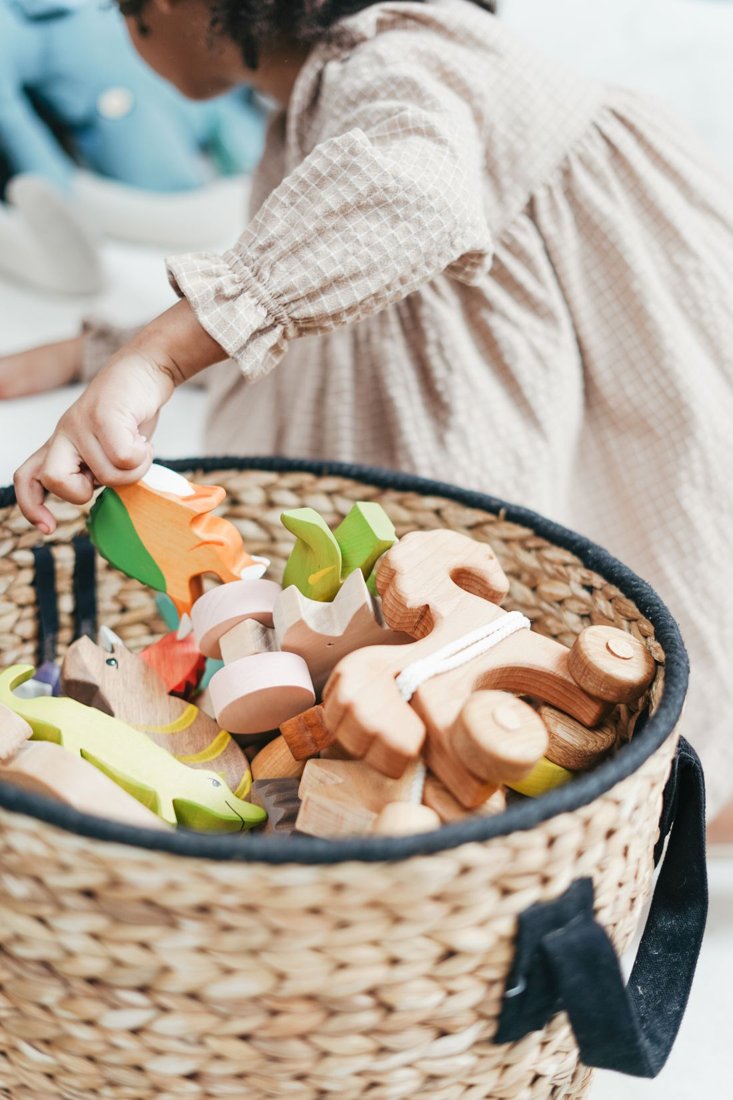 A child choosing wooden toys from a basket.